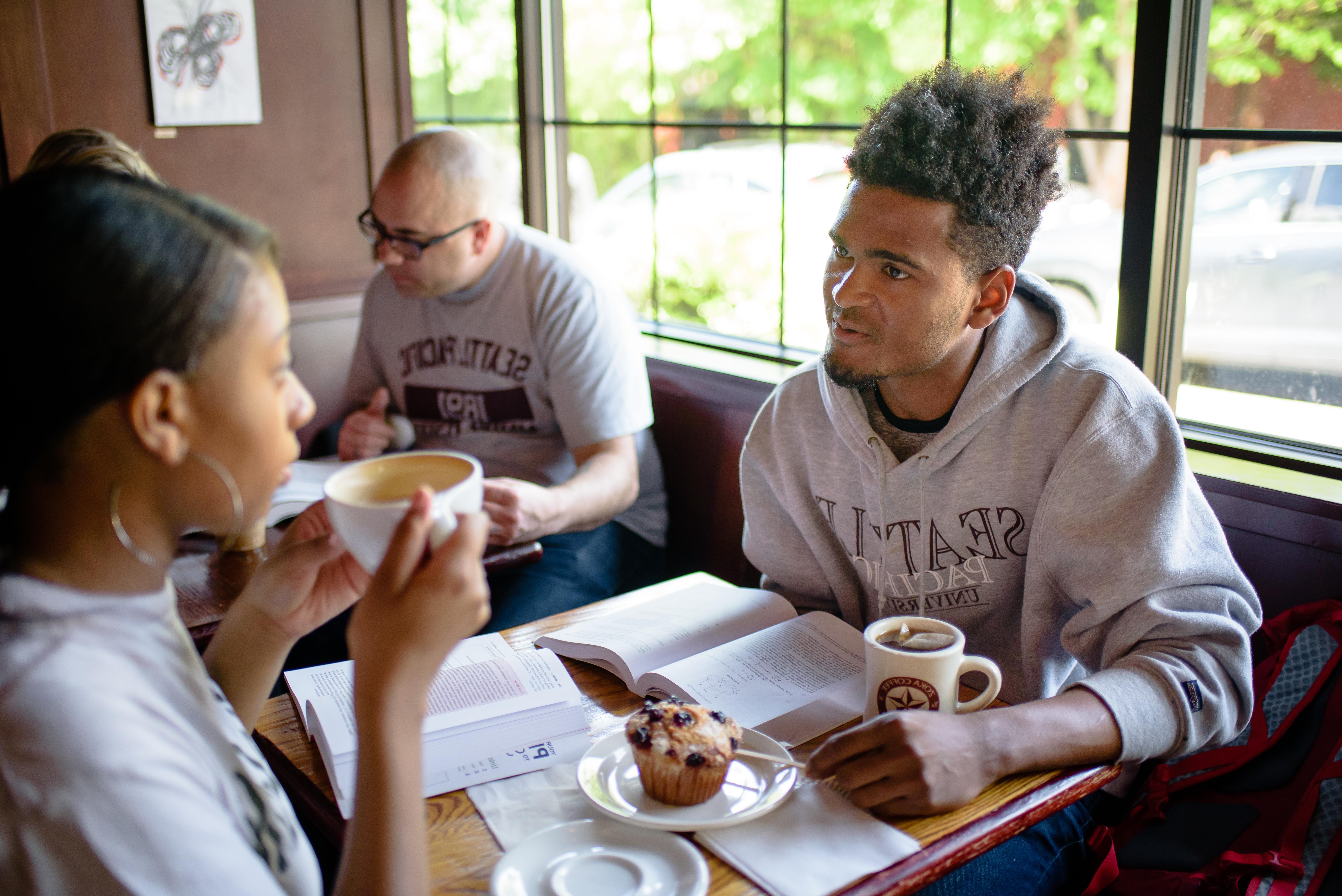 Two students talking at a cafe table